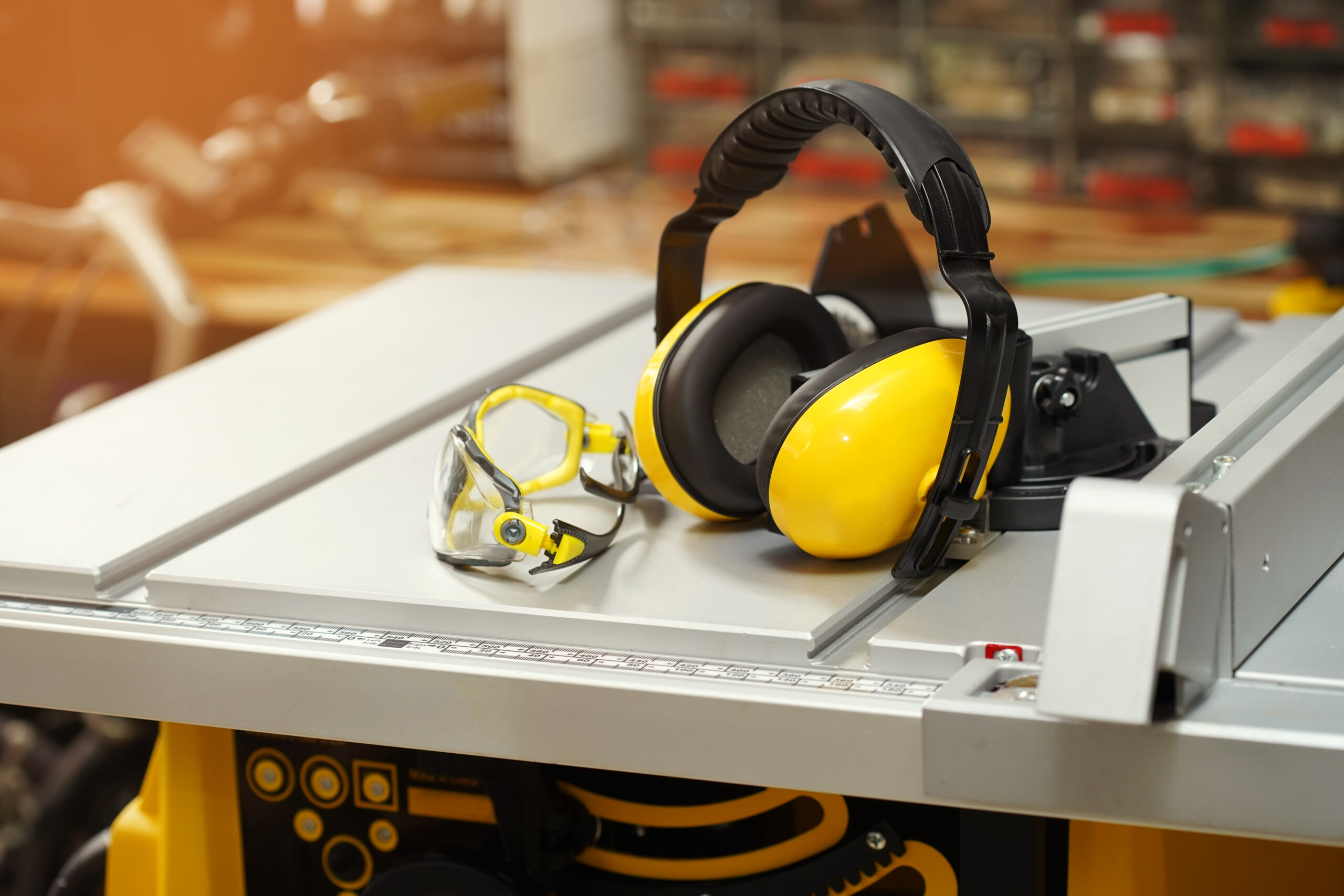 Earmuffs and Safety glasses on Electric saw table in workshop .Work safety concept . selective focus